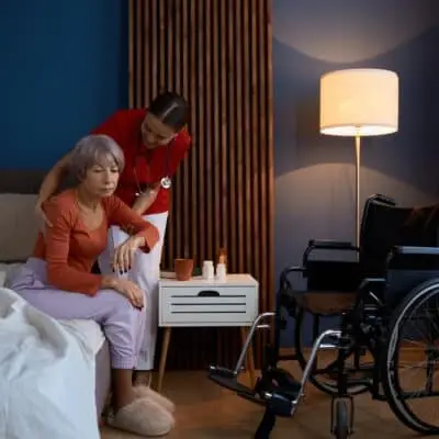 Caregiver assisting elderly woman at home.