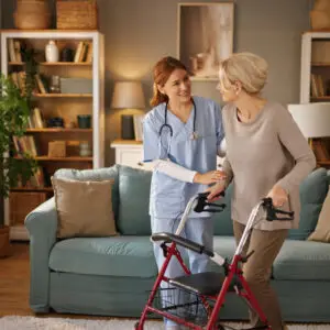 Nurse assisting elderly woman with walker.