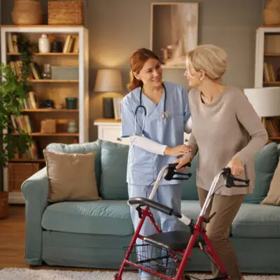Nurse assisting elderly woman with walker.