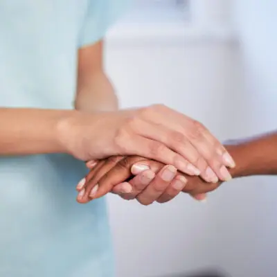 Close up of nurse holding patient's hand during difficult diagnosis, counselling